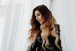 linda mulher sexy de cabelo comprido castanho cacheado posando na cama