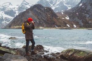 fotógrafo viajante nas rochas contra o fundo do mar e da montanha foto