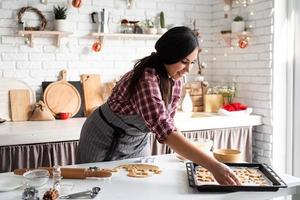 jovem morena fazendo biscoitos na cozinha foto
