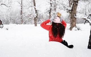 retrovisor de uma mulher morena sentada em um parque nevado na neve foto