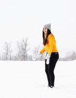 jovem morena brincando com a neve no parque foto