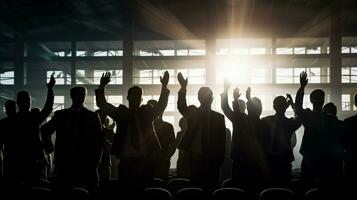 silhuetas do empresários aplaudindo dentro retroiluminado auditório foto