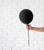 mão de uma mulher segurando um balão preto sobre fundo branco foto