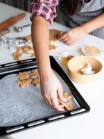 mulher com as mãos assando biscoitos na cozinha foto