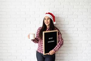 mulher com chapéu de Papai Noel com quadro de carta preto foto