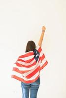 jovem mulher com bandeira americana, braço levantado, vista de trás foto