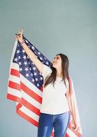 mulher jovem e bonita com bandeira americana sobre fundo azul foto