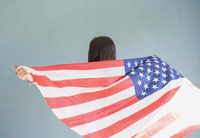 mulher jovem e bonita com bandeira americana sobre fundo azul foto