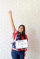 mulher com bandeira americana segurando mesa de luz com palavras feliz 4 de julho foto