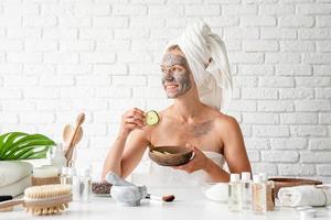 mulher aplicando máscara facial de spa no rosto com uma escova cosmética foto