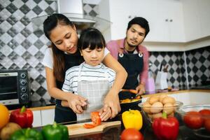 família feliz ajuda a cozinhar a refeição juntos na cozinha em casa. foto