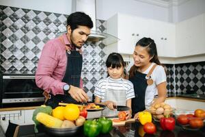 família feliz ajuda a cozinhar a refeição juntos na cozinha em casa. foto