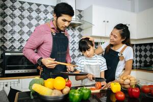 família feliz ajuda a cozinhar a refeição juntos na cozinha em casa. foto