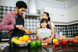 família feliz ajuda a cozinhar a refeição juntos na cozinha em casa. foto