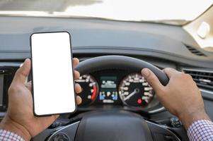 mão segurando a tela em branco do smartphone enquanto dirige o carro. foto