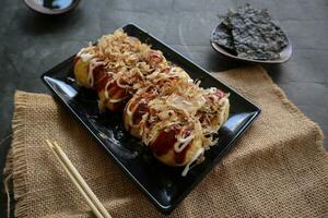 takoyaki é uma japonês comida, fez a partir de trigo farinha massa, polvo carne, ou de outros recheios, servido com molho, maionese e cobertura dentro a Formato do katsuobushi ou madeira peixe aparas de madeira. foto