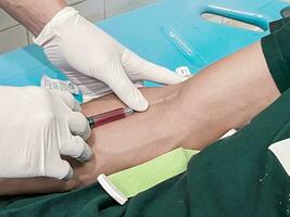 uma masculino enfermeira é injetando uma dor apaziguador anestésico para dentro uma pacientes mão foto