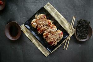 takoyaki é uma japonês comida, fez a partir de trigo farinha massa, polvo carne, ou de outros recheios, servido com molho, maionese e cobertura dentro a Formato do katsuobushi ou madeira peixe aparas de madeira. foto