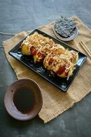 takoyaki é uma japonês comida, fez a partir de trigo farinha massa, polvo carne, ou de outros recheios, servido com molho, maionese e cobertura dentro a Formato do katsuobushi ou madeira peixe aparas de madeira. foto