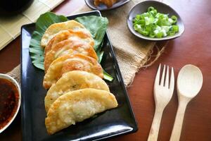 frito wonton. Wonton em prato com Pimenta óleo. camarão ou carne bolinho de massa sopa com mostarda , verde cebolas, em mesa foto