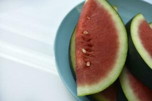 fatiado peças do suculento vermelho Melancia em uma azul placa. suculento frutas dentro verão. foto