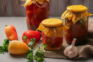 caseiro frascos do em conserva pimentas e tomates em uma rústico de madeira fundo. em conserva e enlatado produtos. Próximo ingredientes para culinária. foto