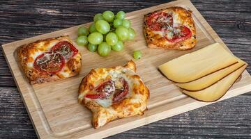 caseiro torta com tomates e queijo mentira em uma de madeira borda Próximo para a uvas e peças do queijo foto