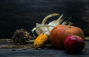 outono colheita conceito com milho abóbora girassóis e maçãs em rústico fundo foto