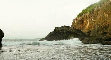 panorâmico Visão do a praia, coral montanhas com ondas dentro a tarde foto