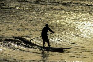 uma homem é equitação uma prancha de surfe dentro a oceano foto