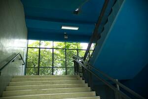 azul superior lado escada com Vejo através parede com árvore e luz solar fundo foto