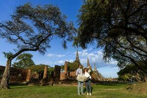 casal de turistas vem visitar o templo wat phra si sanphet, ayutthaya tailândia usando mapas para viagens, férias, férias, lua de mel e conceito de turismo foto