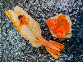 grelhado camarão Sushi e salmão ovas Sushi dentro uma placa. junto, a dois Sushi contraste dentro textura e sabor a concurso calor do camarão justaposto com a legal, estalando sensação do ovas. foto