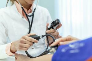 medindo sangue pressão. jovem mulher ter uma Visita com fêmea médico dentro moderno clínica. medindo sangue pressão. pressão medidor. hipertensão e Alto coração taxa foto