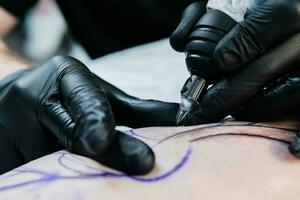 profissional tatuagem artista faz uma tatuagem em a masculino perna foto