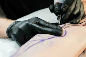 profissional tatuagem artista faz uma tatuagem em a masculino perna foto