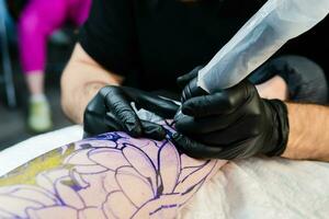 profissional tatuagem artista faz uma tatuagem em a masculino perna foto