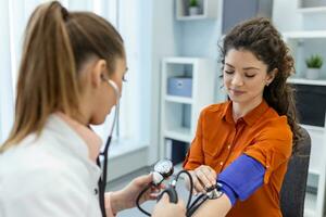 medindo sangue pressão. jovem mulher ter uma Visita com fêmea médico dentro moderno clínica. medindo sangue pressão. pressão medidor. hipertensão e Alto coração taxa foto