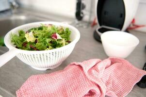 fechar-se do fresco orgânico saudável ervas e verduras dentro a vegetal secador em a cozinha mesa foto