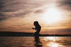 garota de modelo de beleza espirrando água com o cabelo. mulher na água. foto
