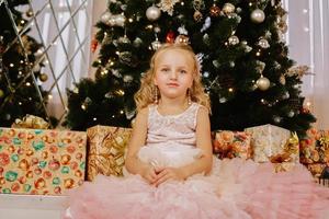 garota em um vestido rosa perto da árvore de natal foto