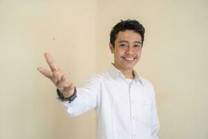 jovem indonésio encaracolado homem vestem branco roupas com miniatura pose. foto