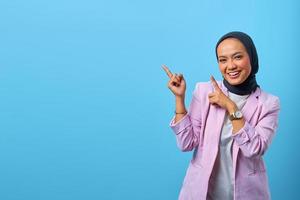 Mulher asiática alegre apontando o dedo para o espaço vazio