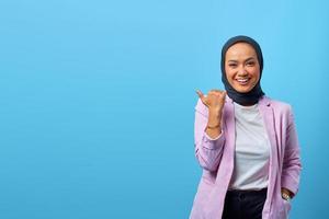 Mulher asiática alegre apontando o dedo para o espaço vazio