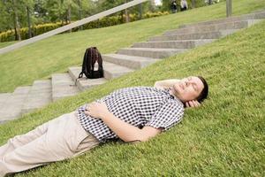 jovem pensativo sentado na grama do parque foto