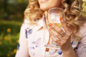 loira feliz segurando uma taça de vinho branco foto