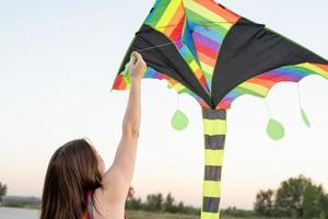 jovem empinando uma pipa em um parque público ao pôr do sol foto