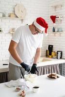 chef com chapéu de Papai Noel cozinhando uma sobremesa na cozinha foto