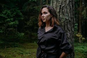 jovem - fechar retrato em uma floresta escura. mulher de camisa preta