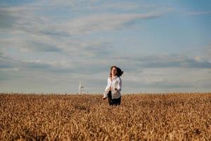 mulher corre em um campo de trigo em um dia de verão. conceito de felicidade e alegria foto